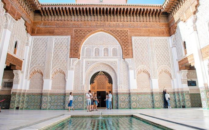 Ben Youssef Madrasa courtyard with intricate tilework and arches, Marrakech, Morocco.