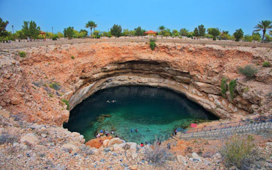 Clear turquoise water in Bimmah sinkhole, Oman, with visitors swimming and exploring.