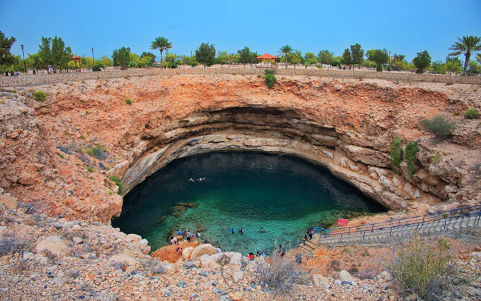 Clear turquoise water in Bimmah sinkhole, Oman, with visitors swimming and exploring.