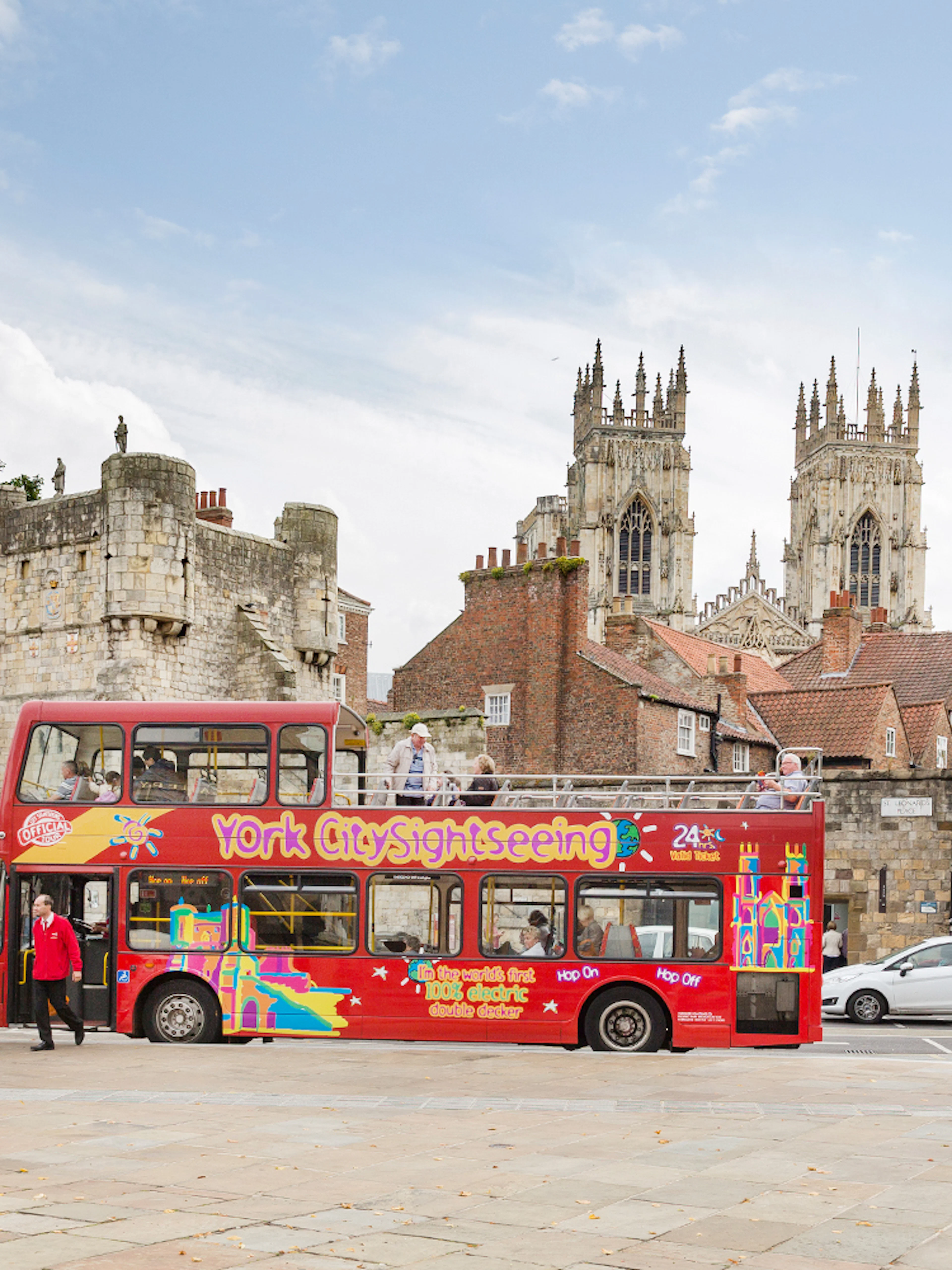 Open-top bus on York Hop-On-Hop-Off Tour near historic city walls and York Minster.