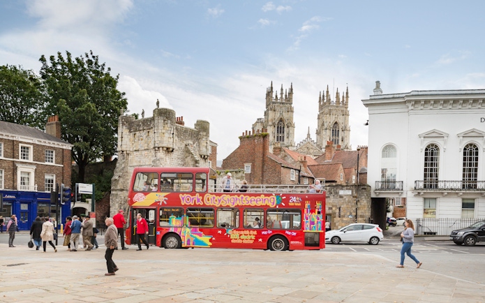 Open-top bus on York Hop-On-Hop-Off Tour near historic city walls and York Minster.