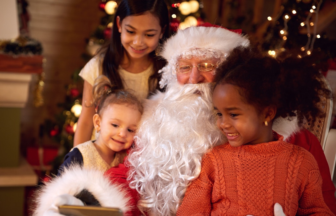Santa Claus taking a selfie with children during Christmas celebration.