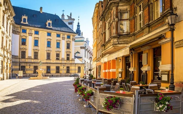 Outdoor café seating in Krakow's historic district, with colorful flowers and classic architecture.