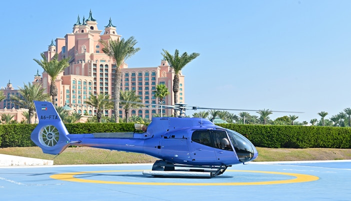 Helicopter on helipad with Atlantis, The Palm hotel in Dubai background.