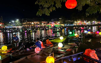 Lantern-lit boat ride on a river at night in Dubai, offering a free herbal drink.