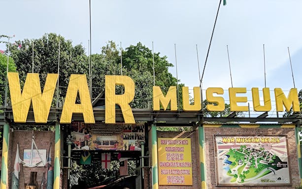 Penang War Museum entrance with large yellow sign and informational displays.