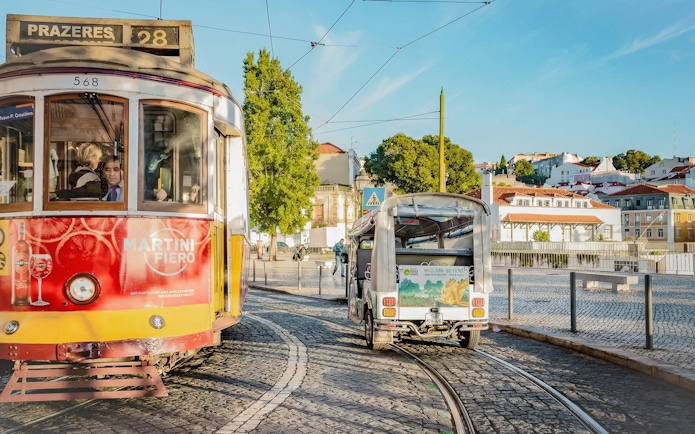 Tuk-Tuk and Tram 28 on Lisbon street, showcasing eco tour route.