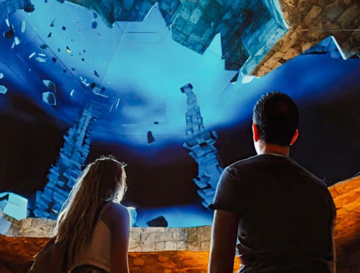 Visitors observing illuminated symbols and stone structures at The Lost World Aquarium.