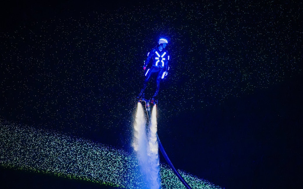 Person flyboarding with neon lights at Symphony of the Sea show.