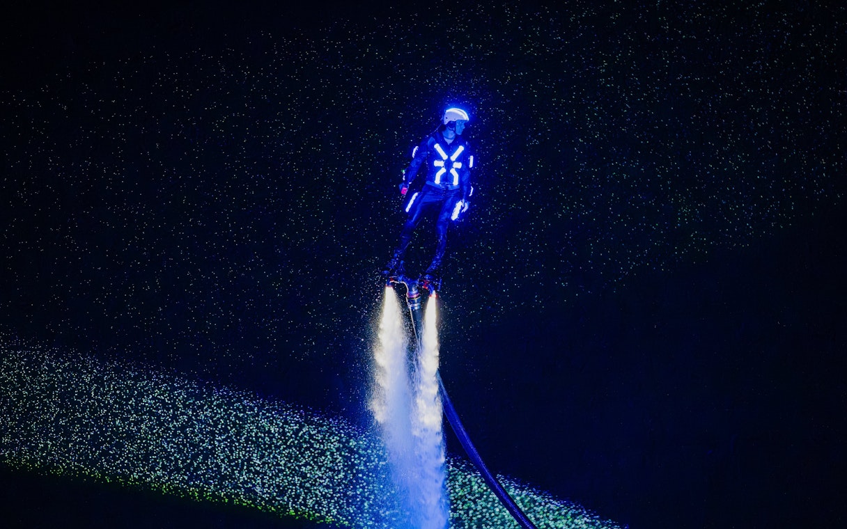Person flyboarding with neon lights at Symphony of the Sea show.