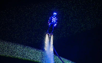 Person flyboarding with neon lights at Symphony of the Sea show.