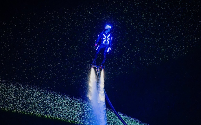Person flyboarding with neon lights at Symphony of the Sea show.