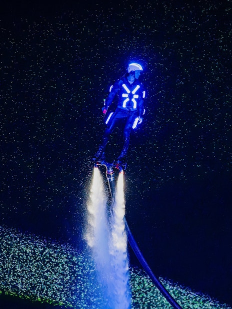 Person flyboarding with neon lights at Symphony of the Sea show.