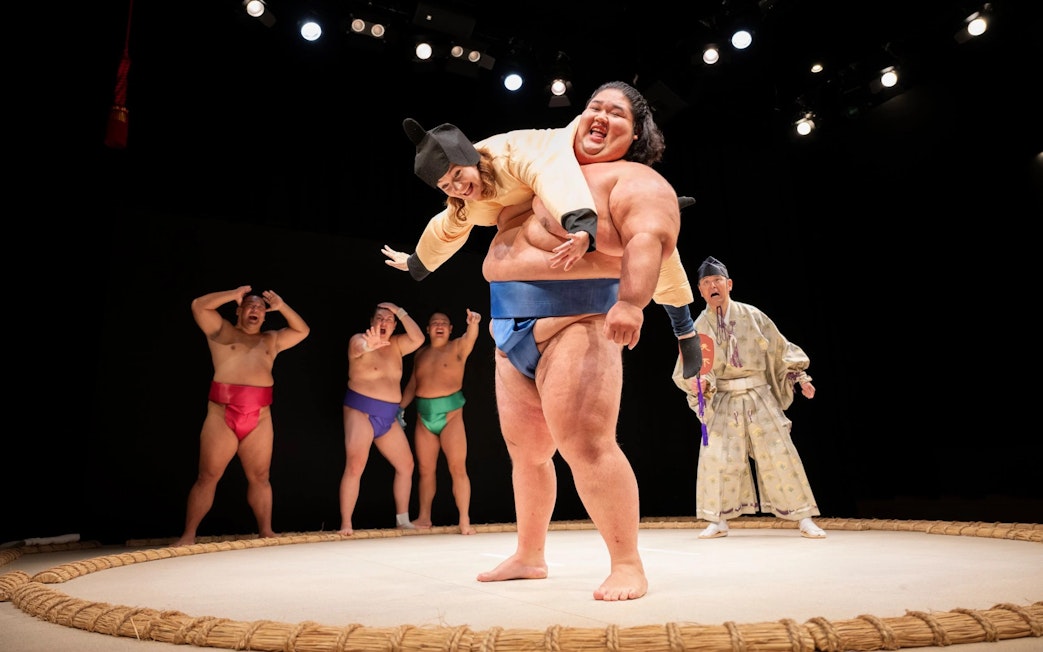 Sumo wrestler lifting performer during show at Hirakuza Ginza, Tokyo.