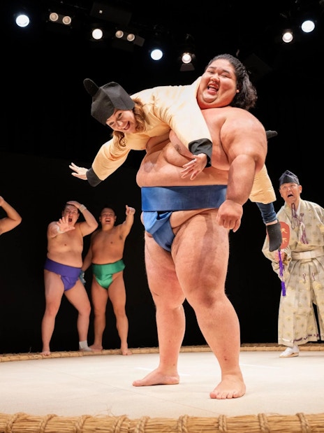 Sumo wrestler lifting performer during show at Hirakuza Ginza, Tokyo.