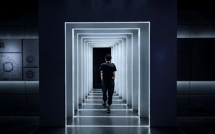 Person walking through illuminated tunnel at AI Dream Immersive Theater.