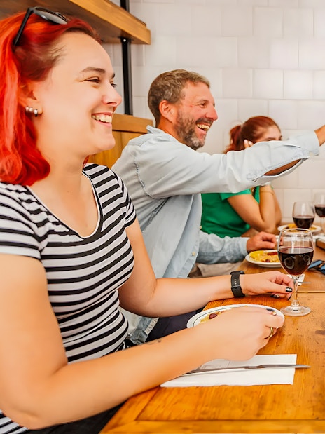 Tourists enjoying food and drinks with a guide at a Lisbon restaurant during a Baixa food walk.