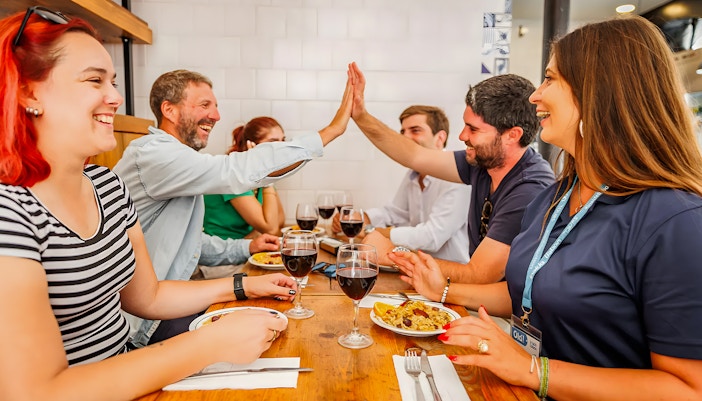 Tourists enjoying food and drinks with a guide at a Lisbon restaurant during a Baixa food walk.