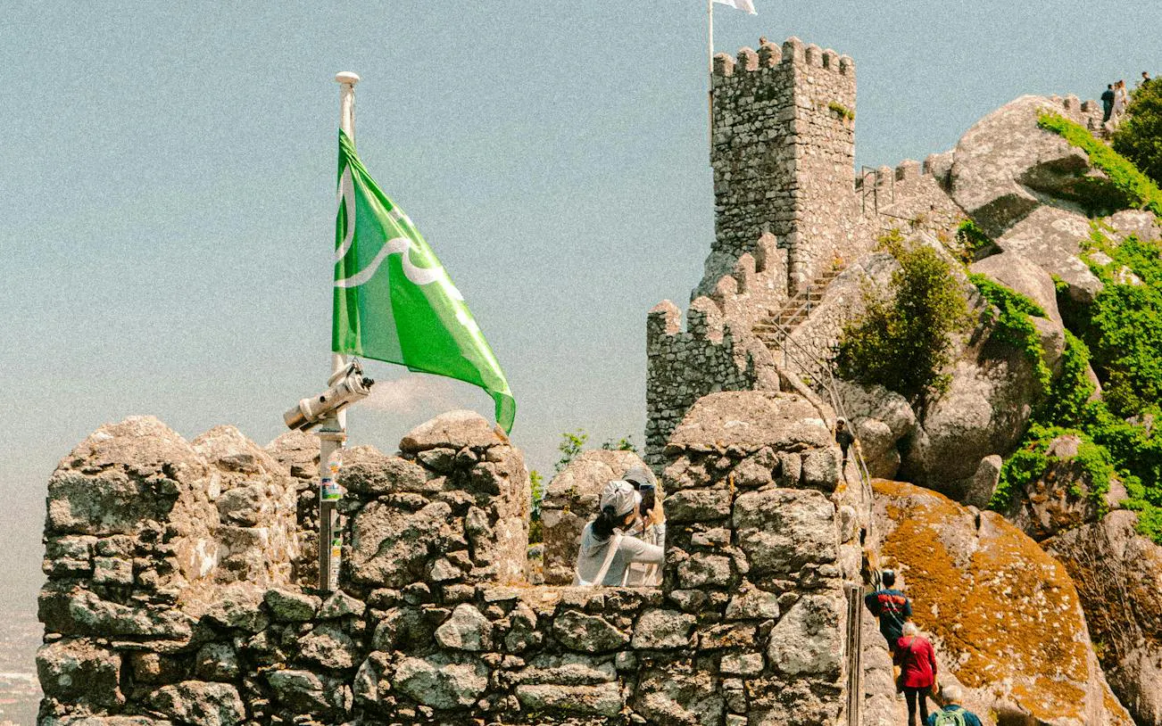 Moorish Castle stone walls with tourists and green flag, Sintra.