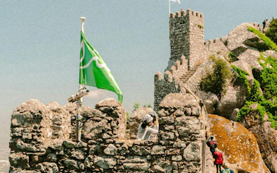 Moorish Castle stone walls with tourists and green flag, Sintra.