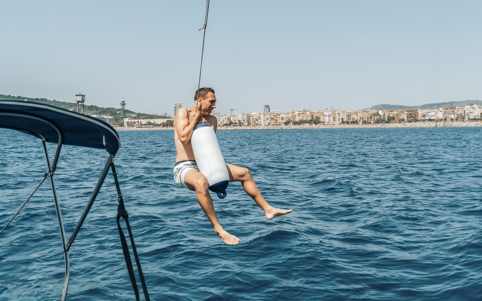 Sailor swinging over the sea near Barcelona on a Magic Sailing Experience.
