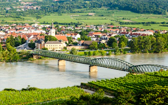 Bridge over the Danube River with the town of Mautern and vineyards in the background.