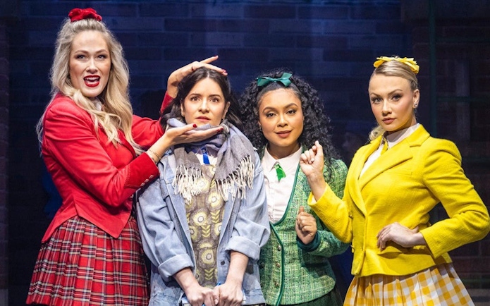 Cast members of Heathers the Musical on West End stage in colorful costumes.