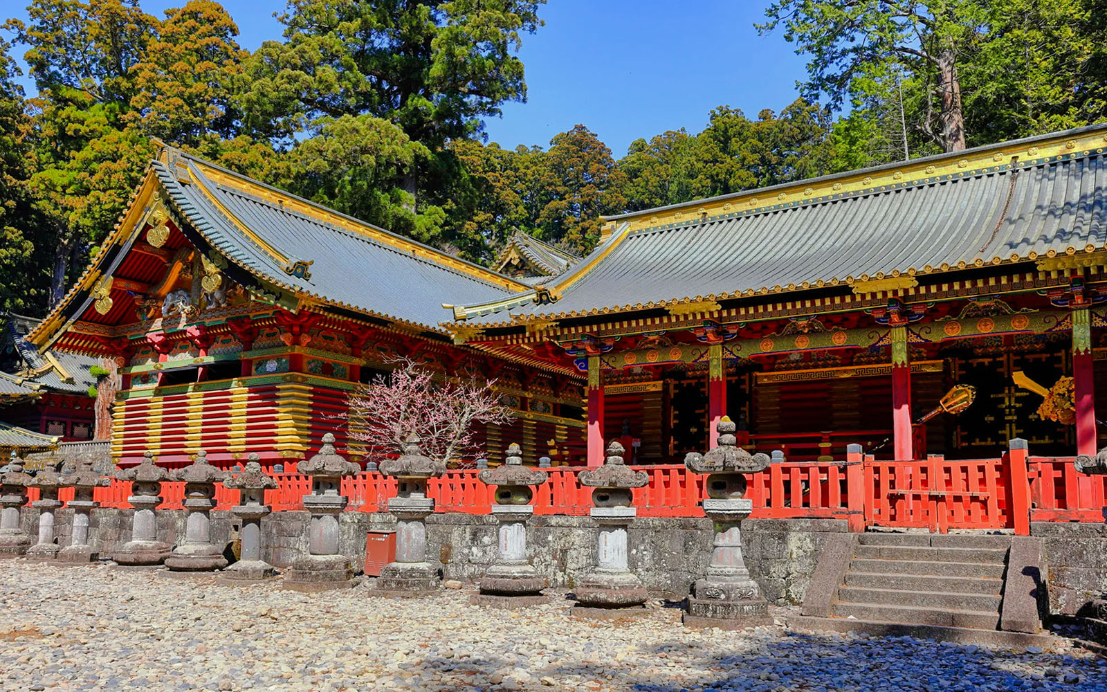Nikkō Tōshō-gū shrine with ornate red and gold architecture, stone lanterns, and surrounding trees.