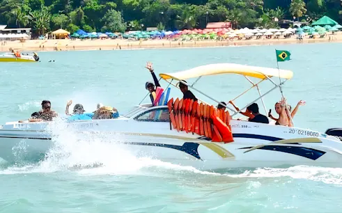 Boat tour with passengers waving near Praia da Pipa beach, Sao Paulo.