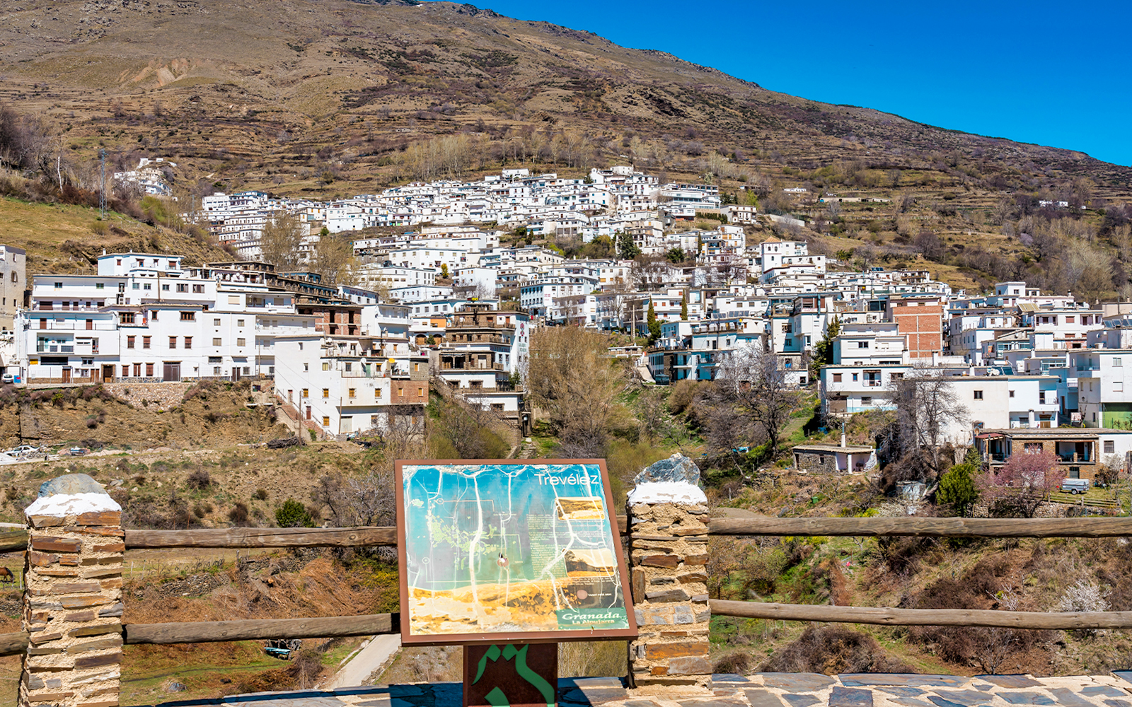 Trevelez village view in La Alpujarra Granadina, Spain, with map sign in foreground.