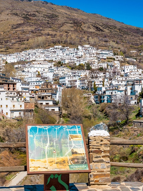 Trevelez village view in La Alpujarra Granadina, Spain, with map sign in foreground.