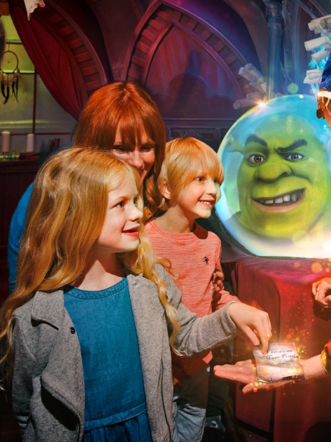 Visitors interacting with a character at Shrek's Adventure London, with Shrek in a crystal ball.