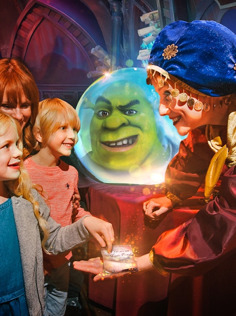 Visitors interacting with a character at Shrek's Adventure London, with Shrek in a crystal ball.