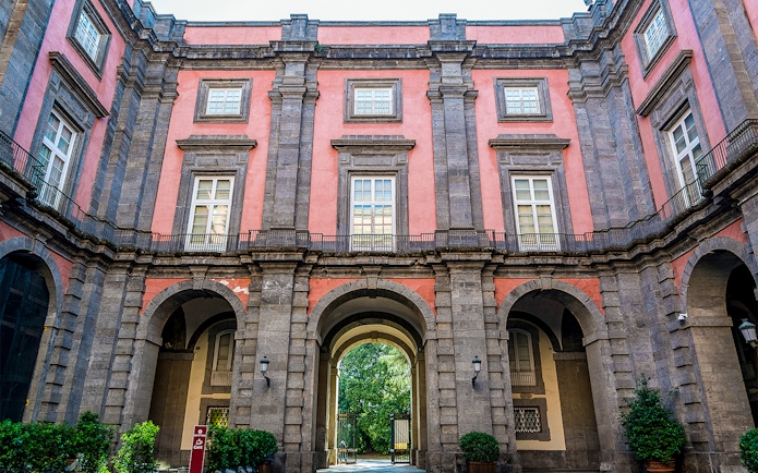 Capodimonte Museum exterior with arched entrance and pink facade in Naples, Italy.