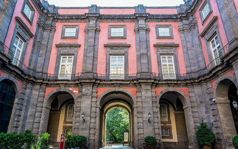 Capodimonte Museum exterior with arched entrance and pink facade in Naples, Italy.