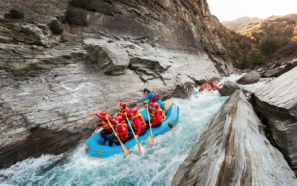 Whitewater rafting on Shotover River, Queenstown, navigating rocky gorge.