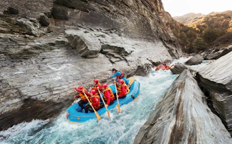 Whitewater rafting on Shotover River, Queenstown, navigating rocky gorge.
