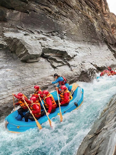 Whitewater rafting on Shotover River, Queenstown, navigating rocky gorge.