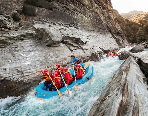 Whitewater rafting on Shotover River, Queenstown, navigating rocky gorge.