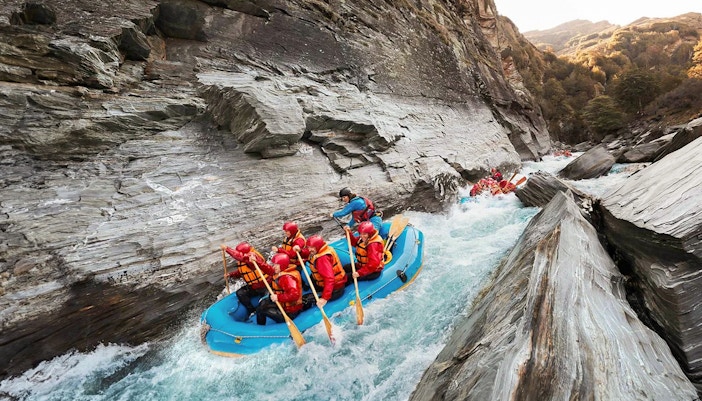 Whitewater rafting on Shotover River, Queenstown, navigating rocky gorge.