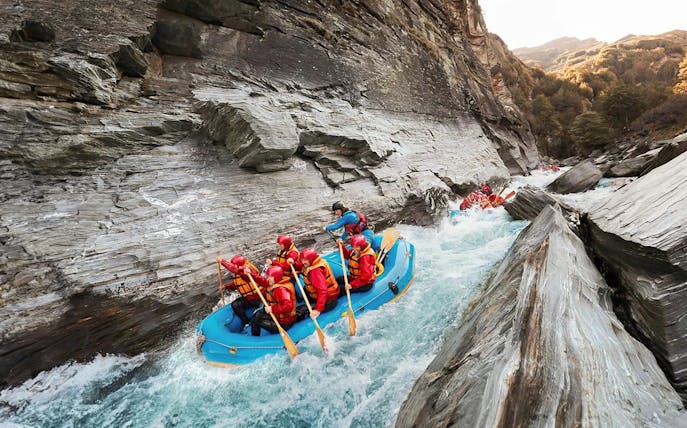 Whitewater rafting on Shotover River, Queenstown, navigating rocky gorge.