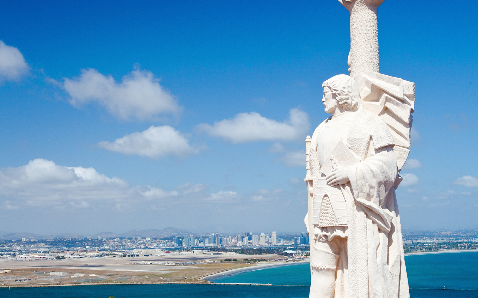 Statue at Cabrillo National Monument overlooking San Diego skyline and ocean.
