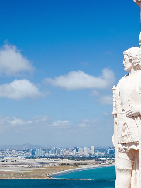 Statue at Cabrillo National Monument overlooking San Diego skyline and ocean.