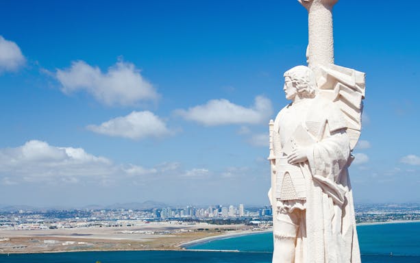 Statue at Cabrillo National Monument overlooking San Diego skyline and ocean.