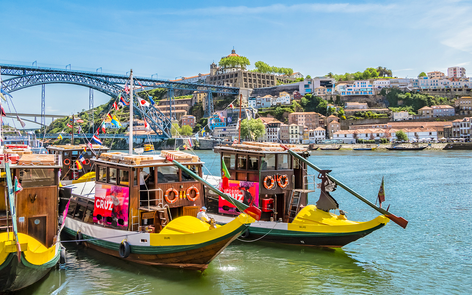 Traditional boats on Douro River with Dom Luís I Bridge in Porto, Portugal.