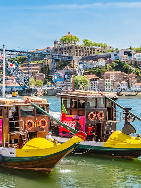 Traditional boats on Douro River with Dom Luís I Bridge in Porto, Portugal.