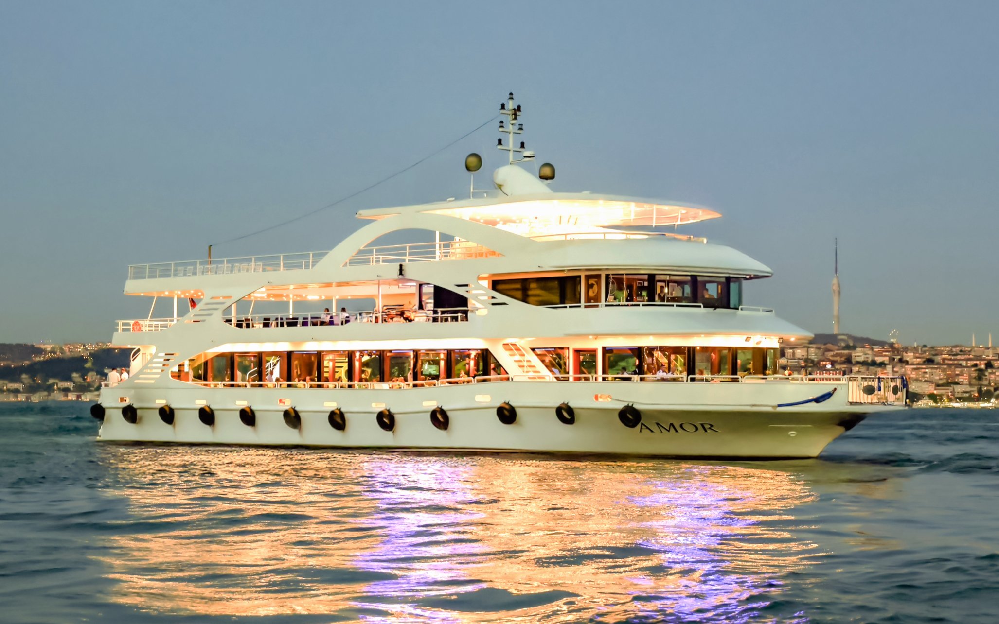 Luxury yacht on Bosphorus dinner cruise, Istanbul skyline in background.