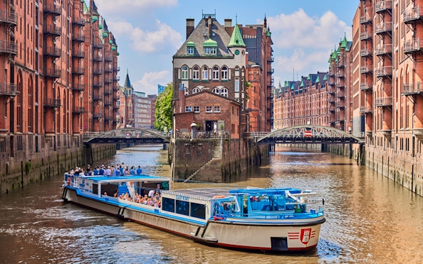 Hop-on hop-off tour boat cruising through Hamburg's Speicherstadt district.
