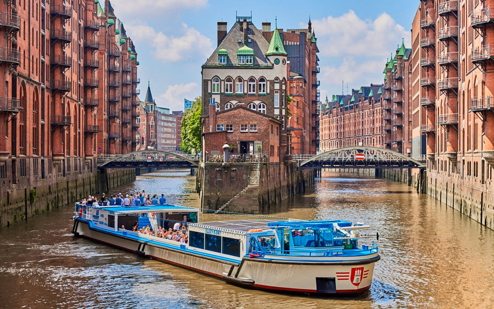 Hop-on hop-off tour boat cruising through Hamburg's Speicherstadt district.