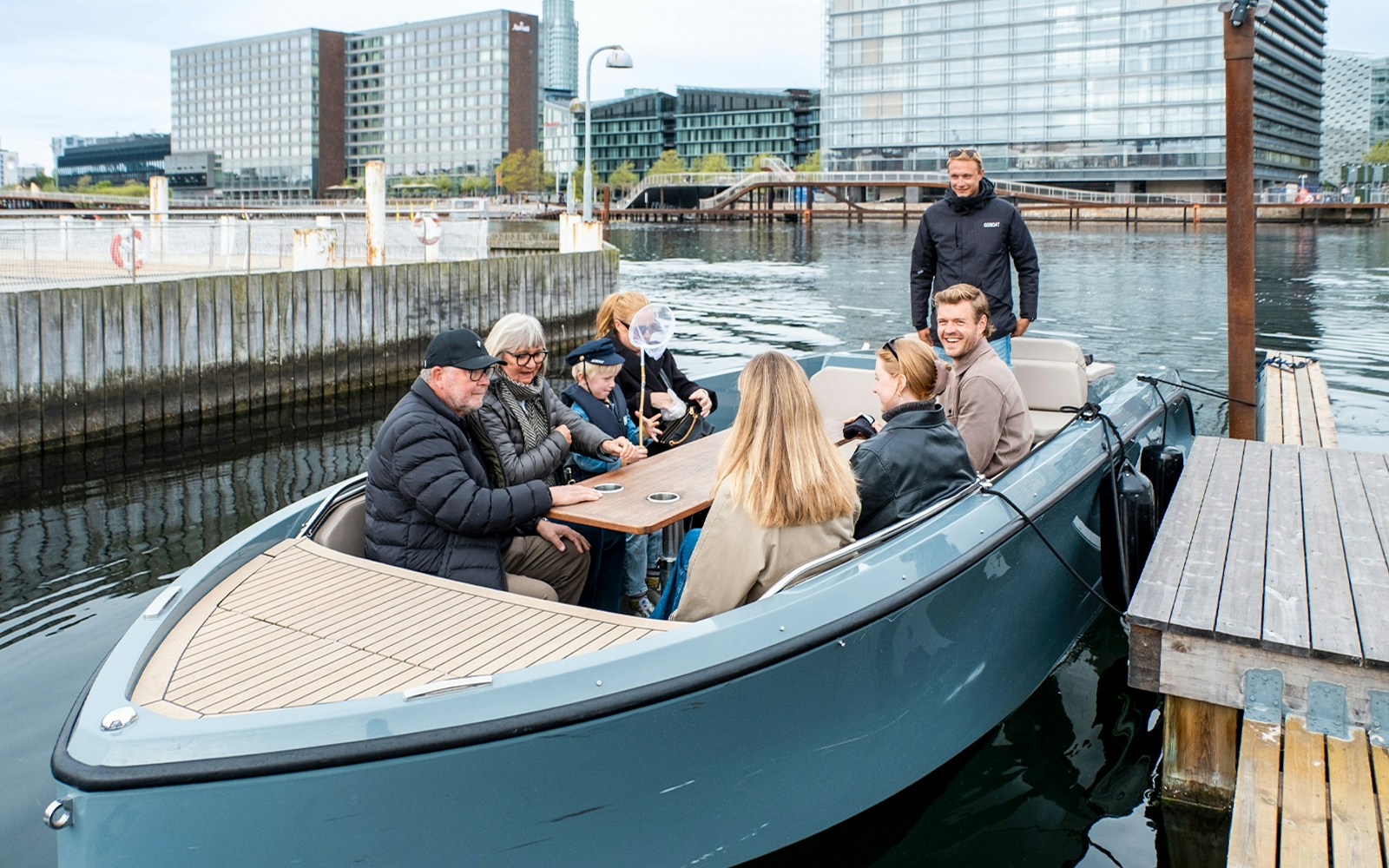 Guests on electric boat tour in Copenhagen, captain pedaling through city canals.